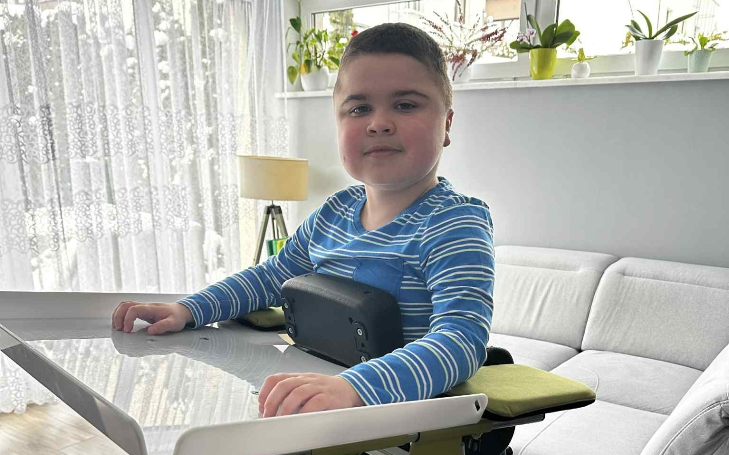 
        Chłopiec przy stole, uśmiechający się do kamery.
    