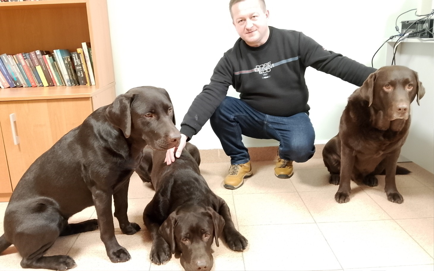 
        Mężczyzna z trzema labradorami, pozujący do zdjęcia.
    