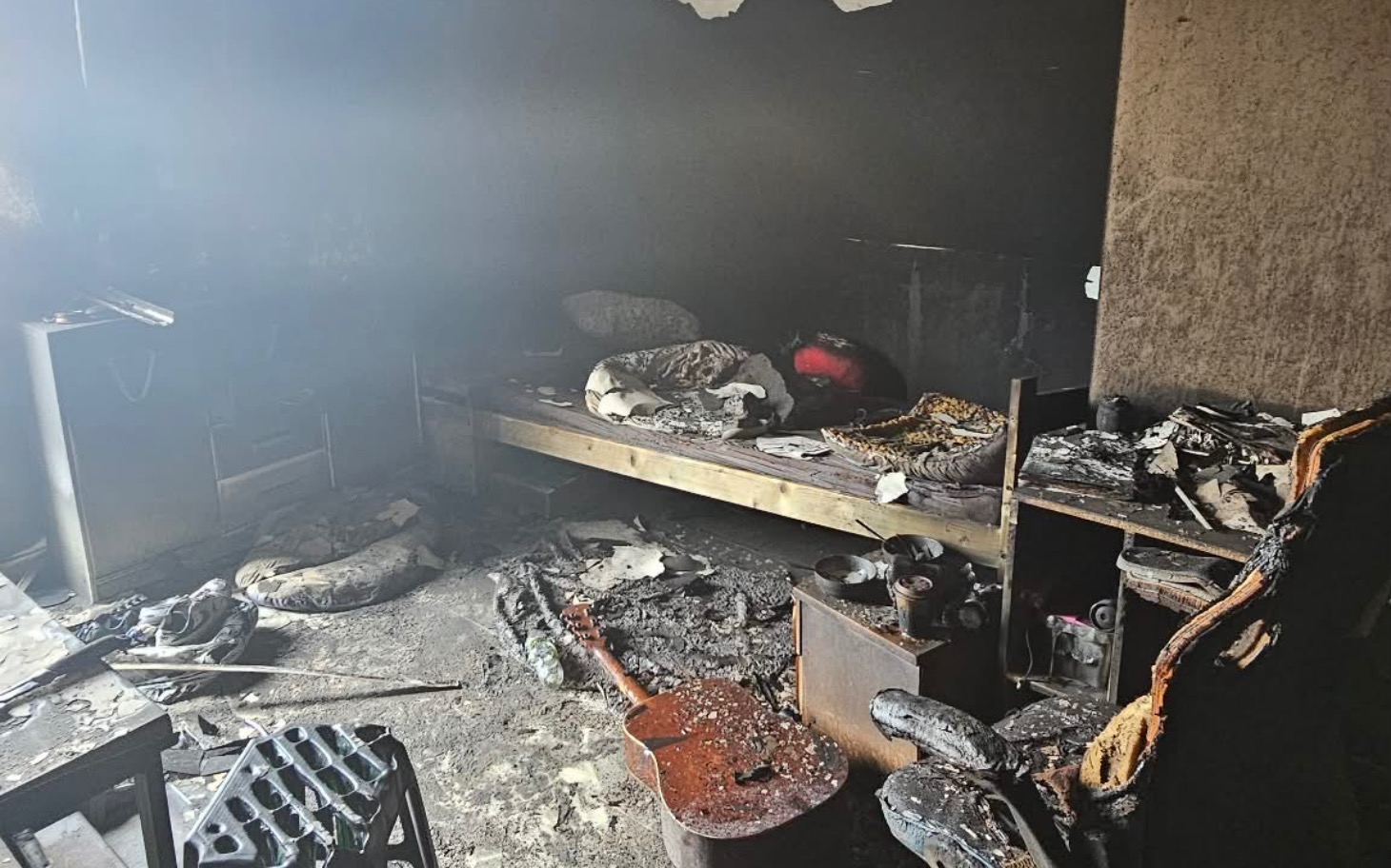 
        Zniszczony pokój po pożarze, z uszkodzonymi meblami.
    