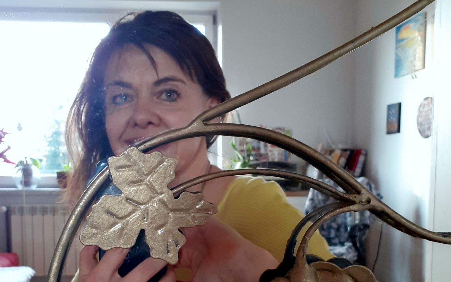 Kobieta trzymająca ozdobę, uśmiechająca się do lustra.