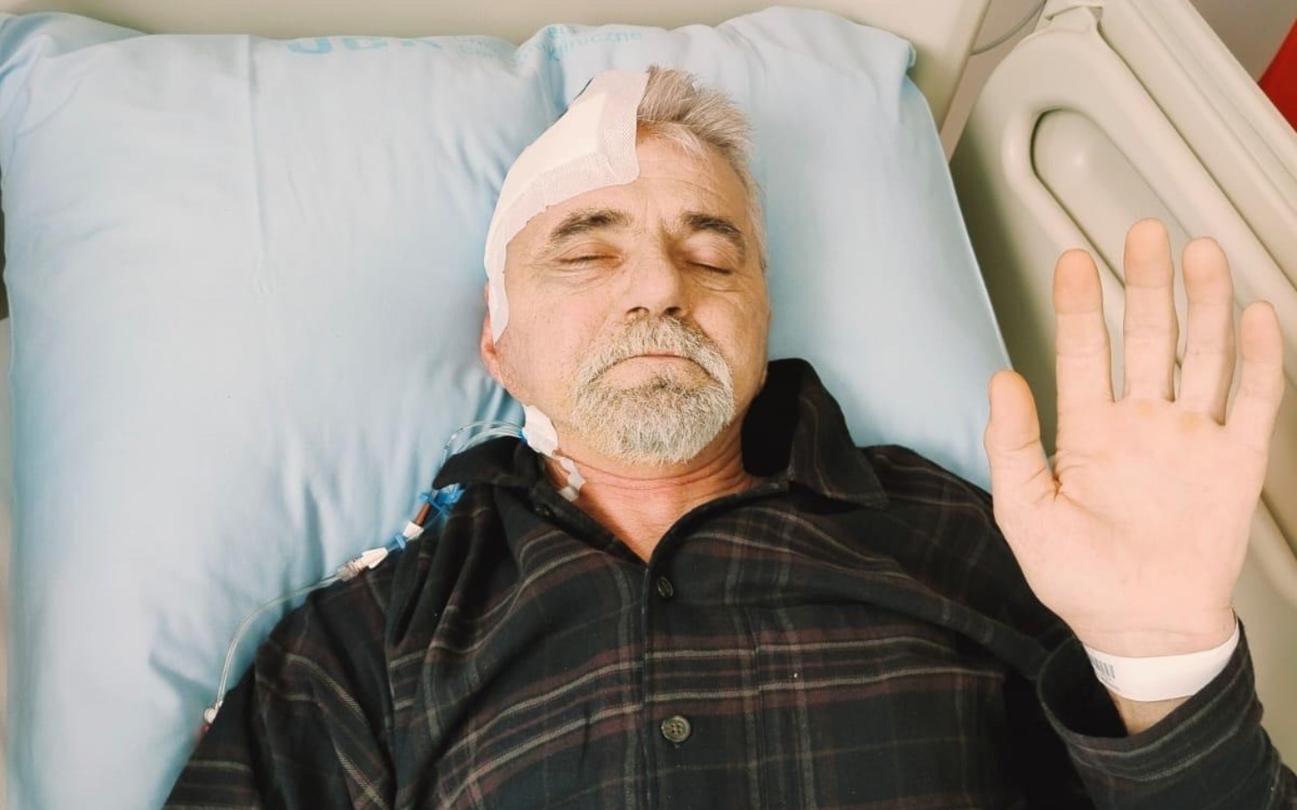 
        Mężczyzna leżący w szpitalu, z opatrunkiem na głowie.
    