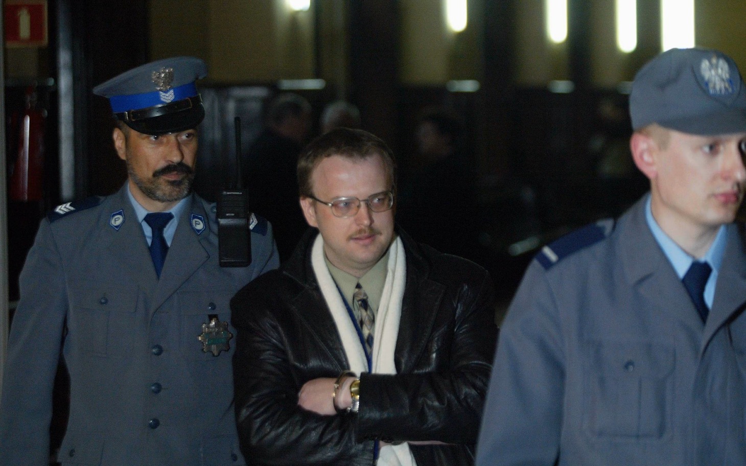 
        Trzech policjantów w sądzie, jeden z nich w okularach.
    