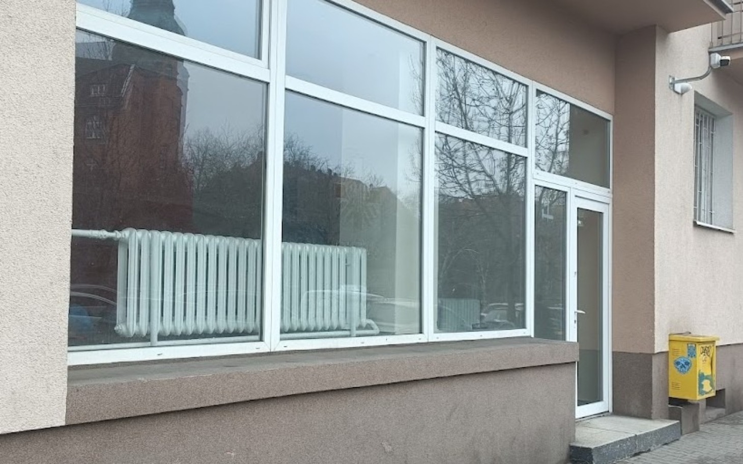 
        Budynek z dużymi oknami, widok na zewnątrz.
    