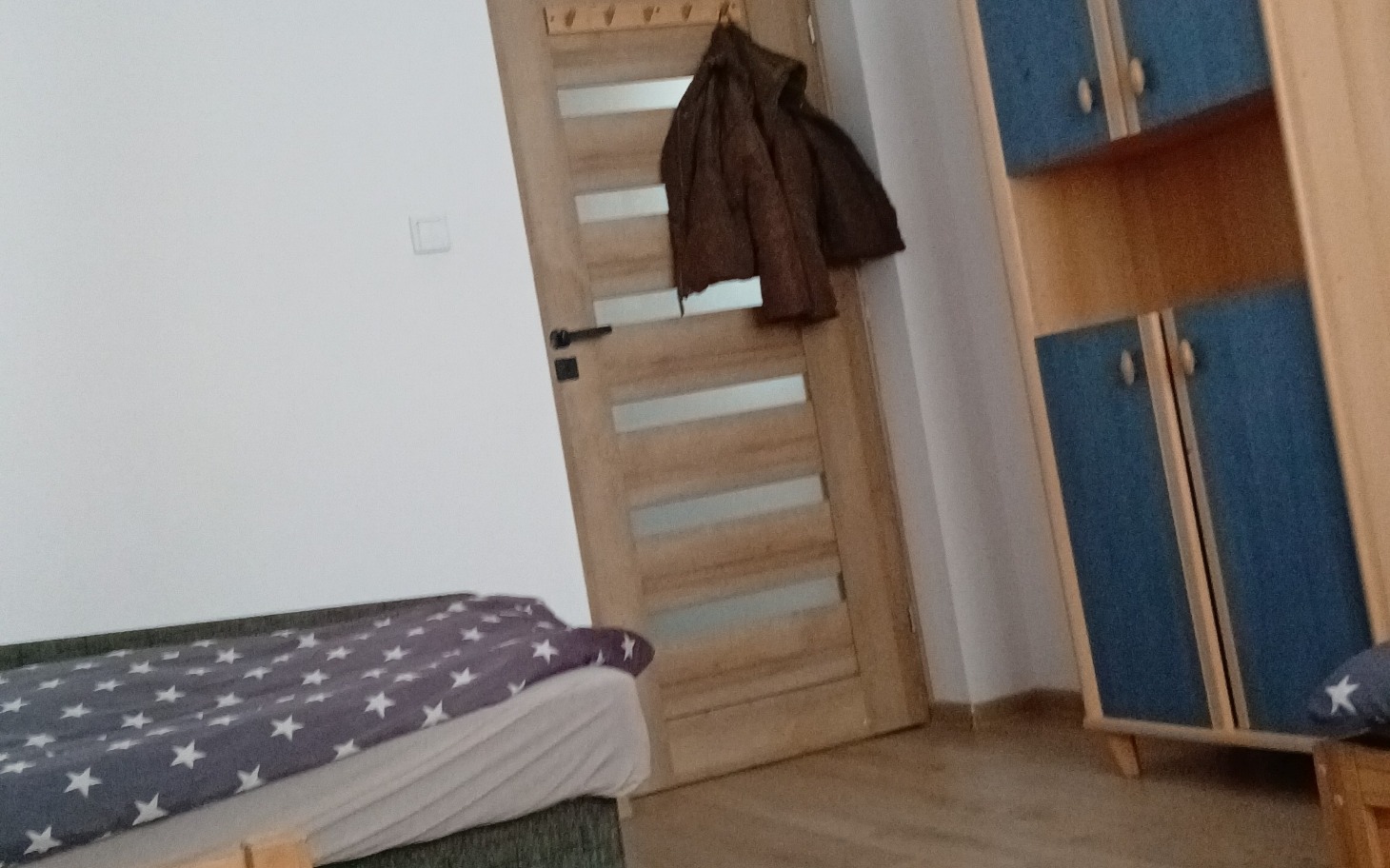 
        Wnętrze pokoju z łóżkiem i drzwiami.
    