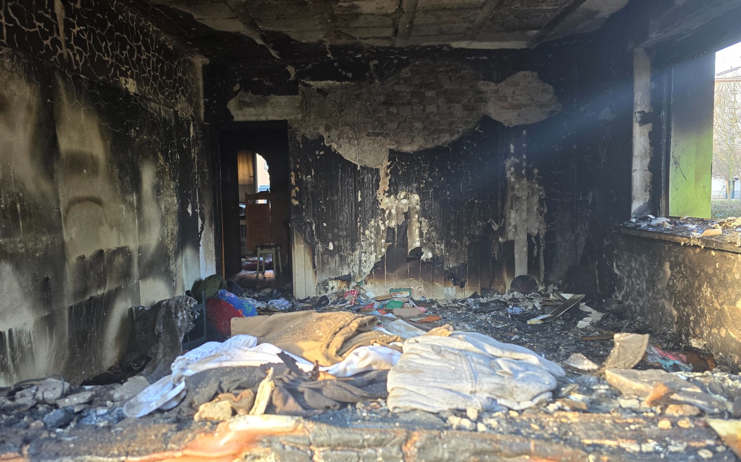 
        Zniszczony pokój po pożarze, z popiołem i zniszczeniami.
    