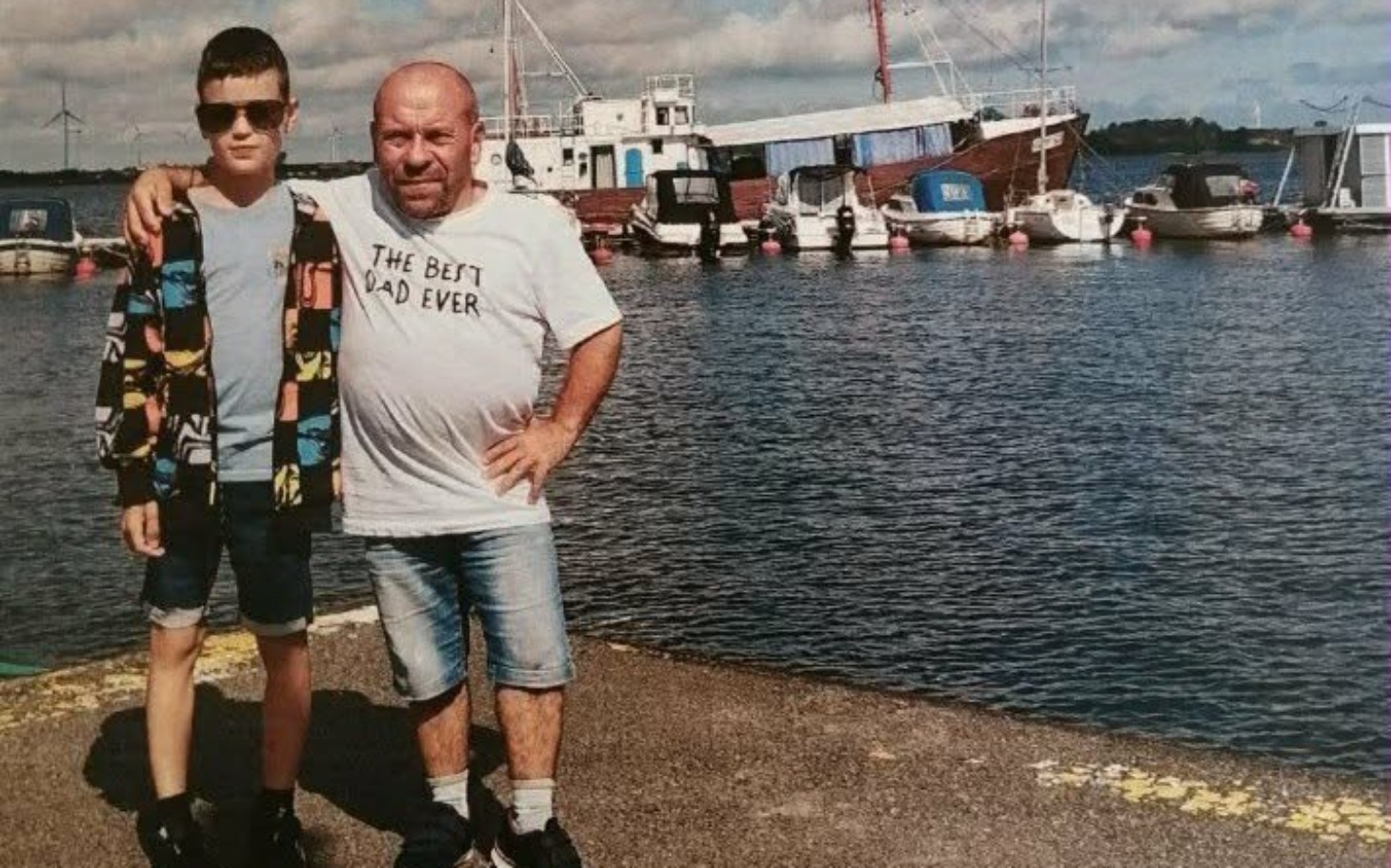 
        Mężczyzna z dzieckiem na tle portu, wspólne chwile.
    