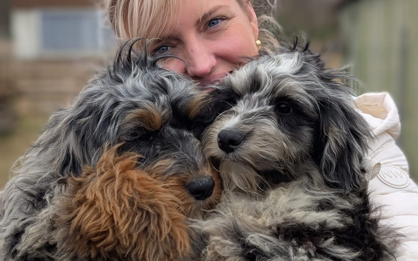 
        Kobieta przytulająca dwa urocze psy.
    