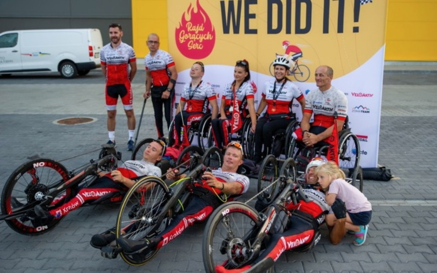 
        Zespół sportowców na wózkach inwalidzkich, pozujący do zdjęcia.
    