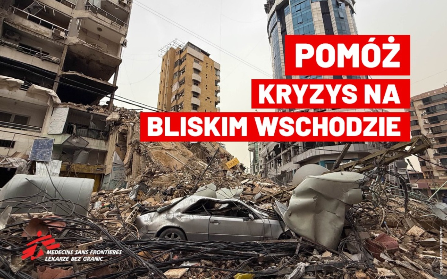 Zniszczony budynek po katastrofie, z wrakiem samochodu w tle.