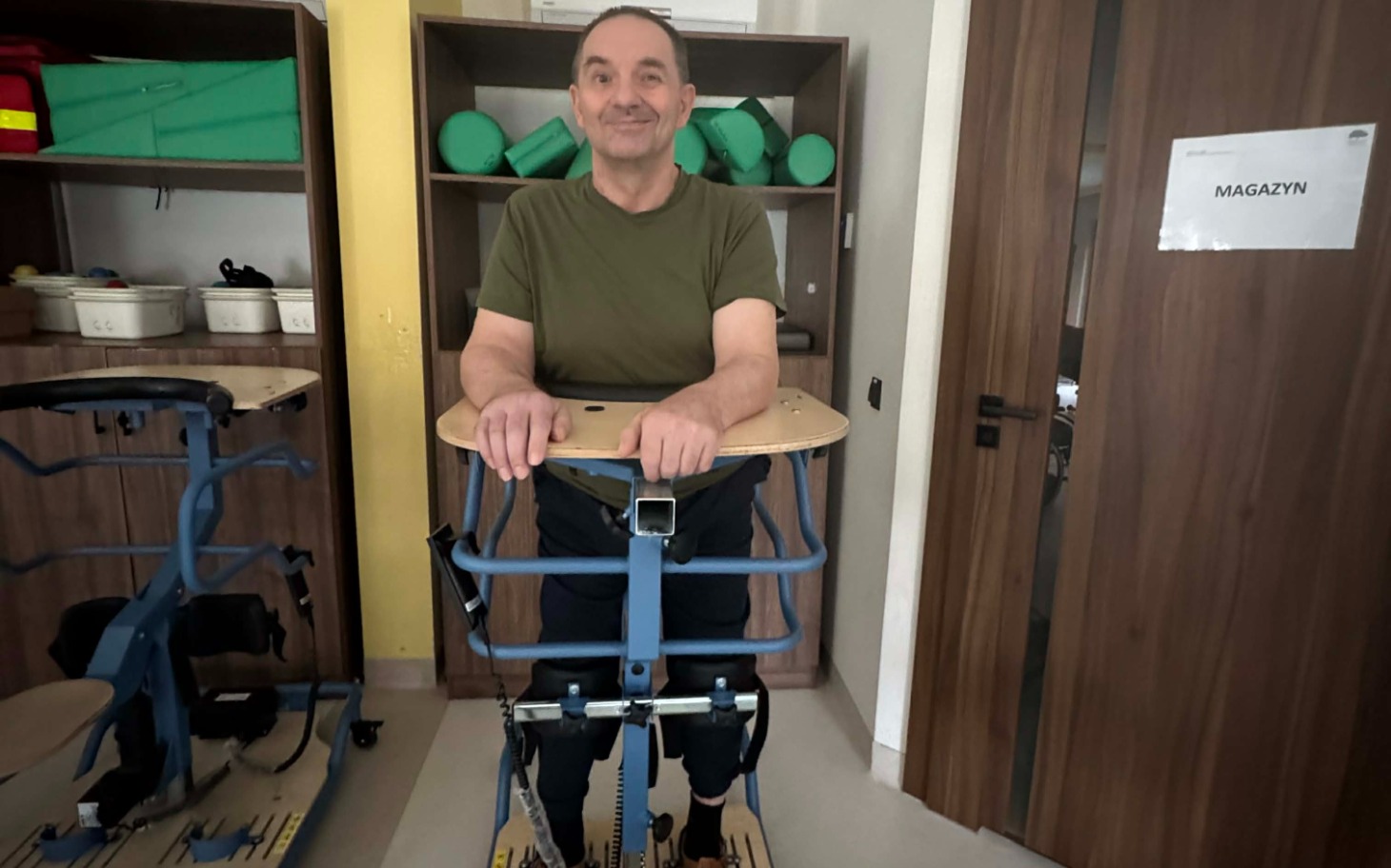 
        Mężczyzna korzystający z urządzenia wspomagającego chodzenie.
    