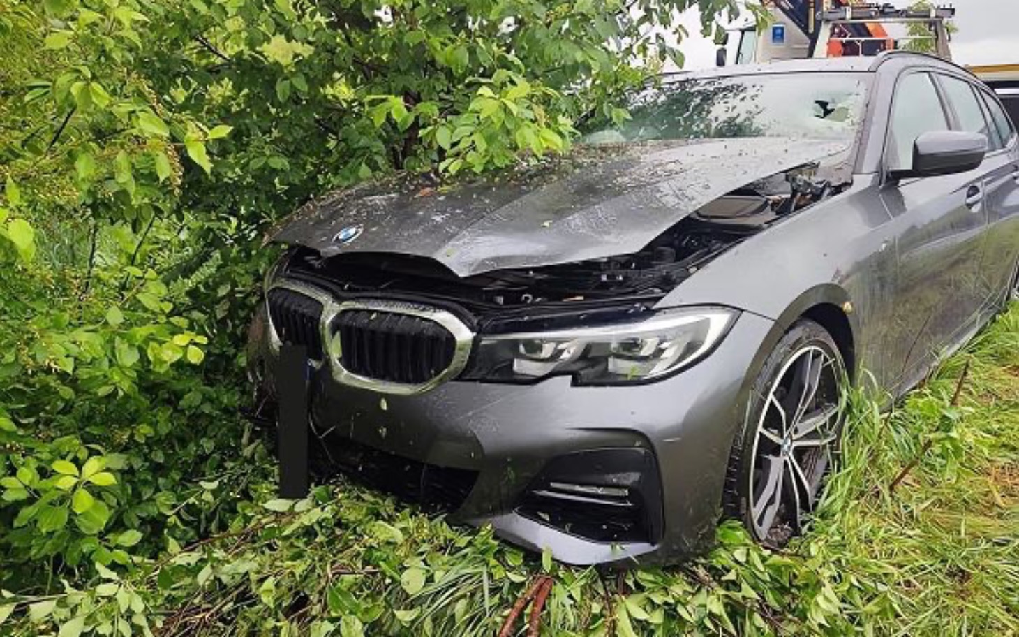 
        Uszkodzony samochód BMW w zaroślach po wypadku.
    