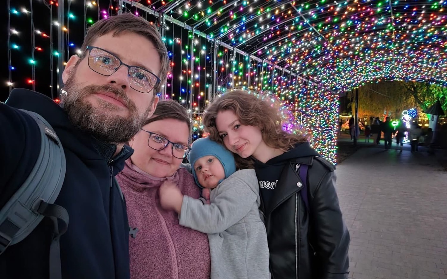 
        Rodzina pozująca w świetle kolorowych lampek na festiwalu.
    