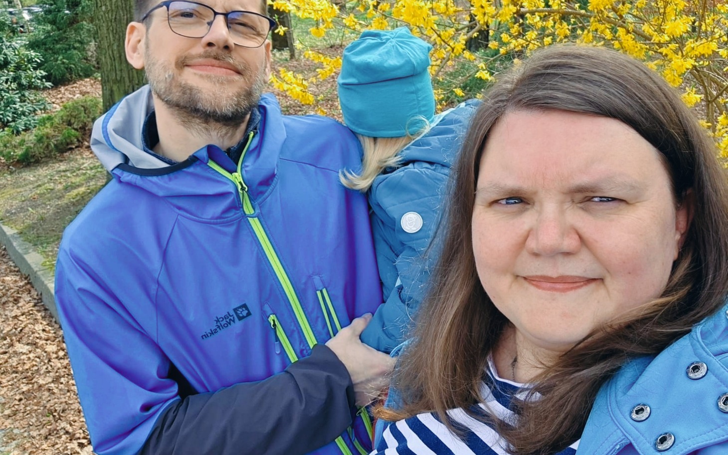 
        Rodzina na spacerze w parku, otoczeni żółtymi kwiatami.
    