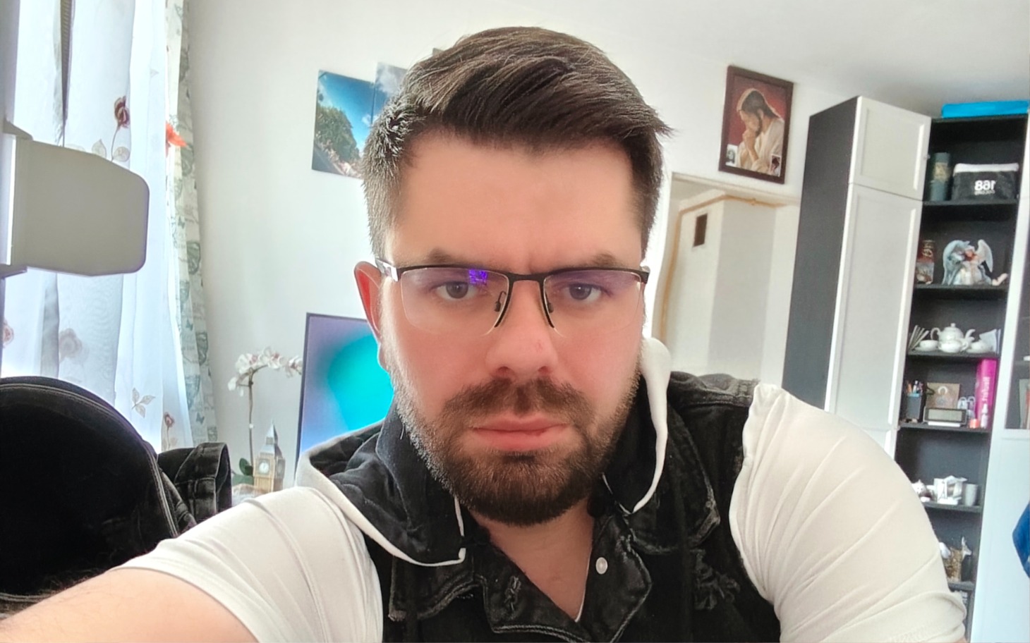 
        Mężczyzna w okularach, selfie w jasnym pomieszczeniu.
    