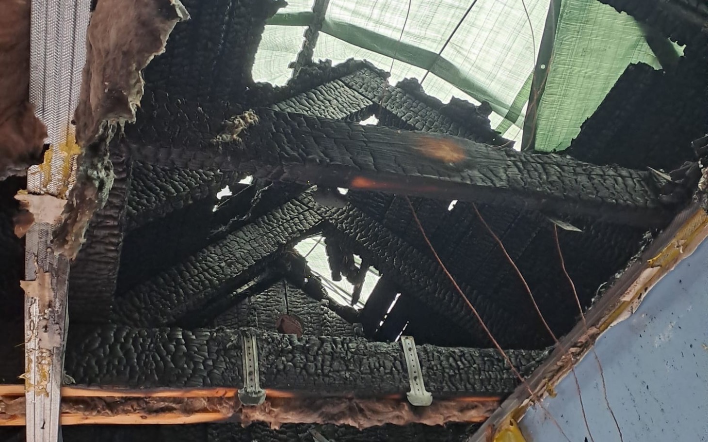 
        Zniszczony dach budynku po pożarze, z widocznymi uszkodzeniami.
    