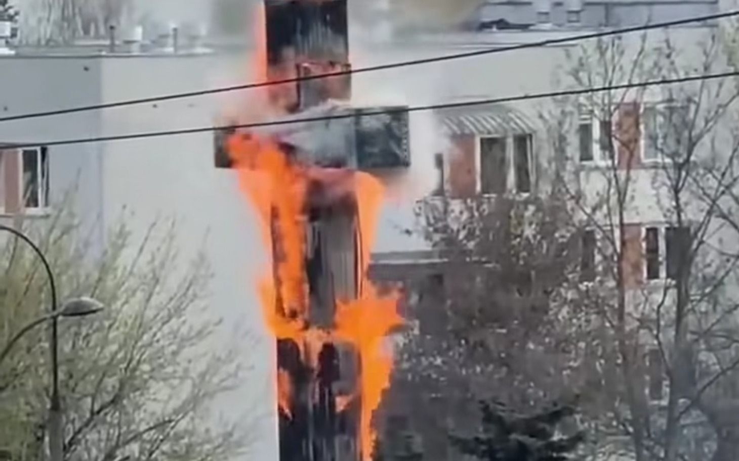 
        Płonący krzyż na tle budynków mieszkalnych.
    