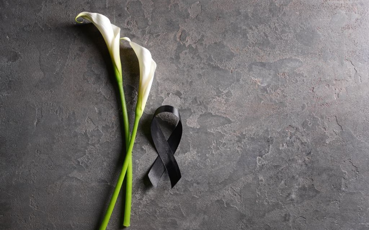 
        Kwiaty i czarna wstążka, symbol żalu i pamięci.
    