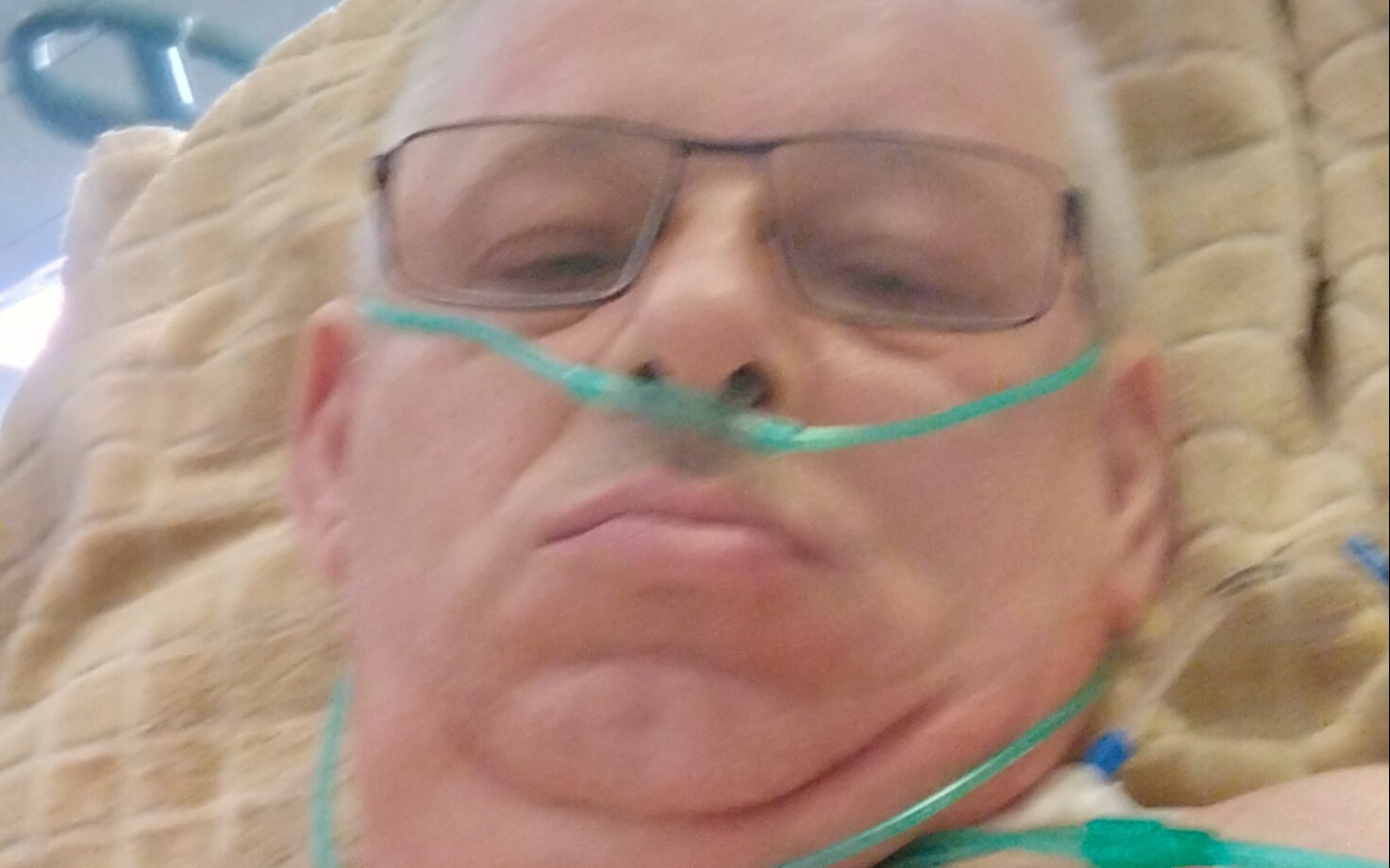 
        Mężczyzna w szpitalu z tlenem na twarzy.
    