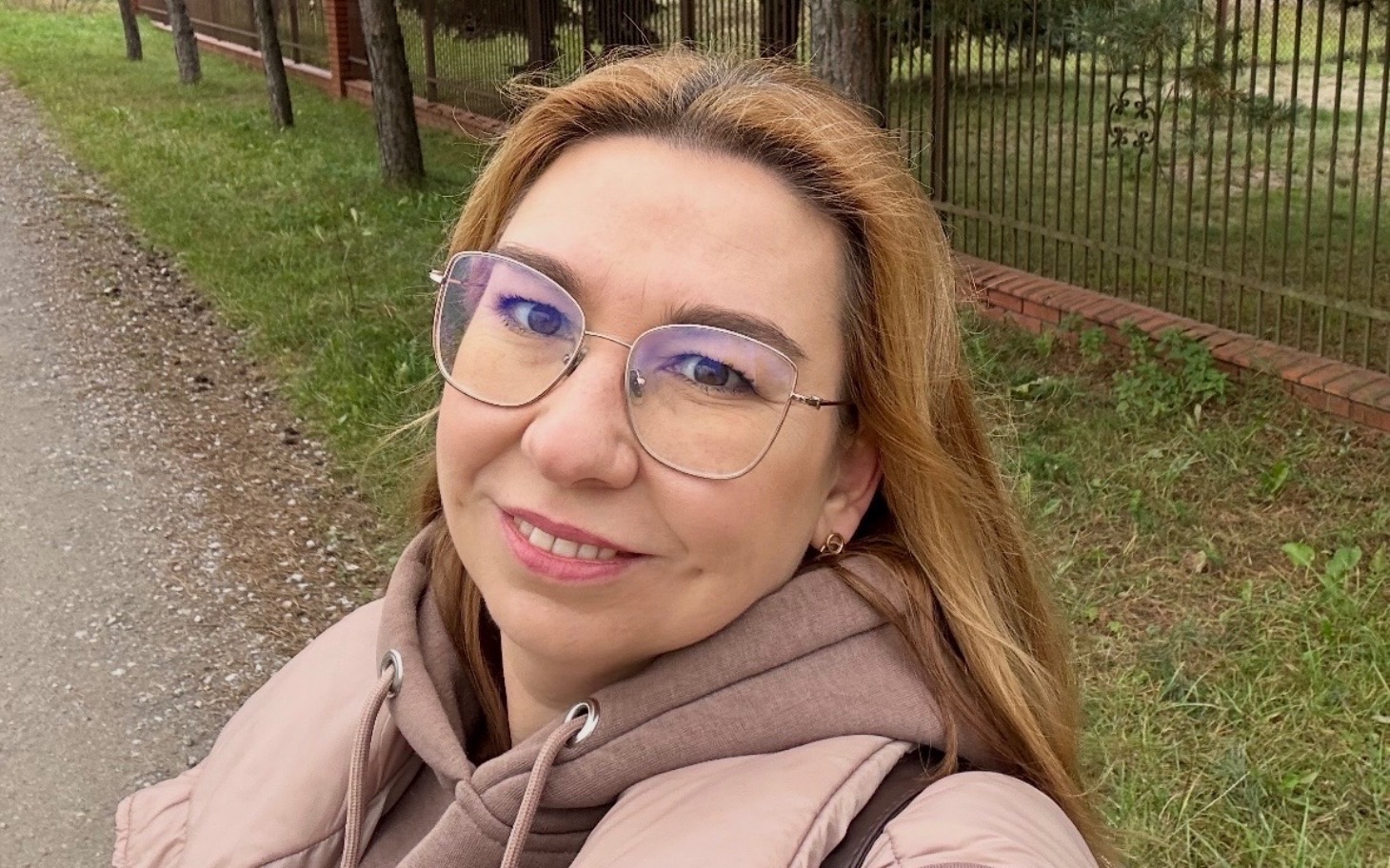 
        Uśmiechnięta kobieta spacerująca w parku.
    