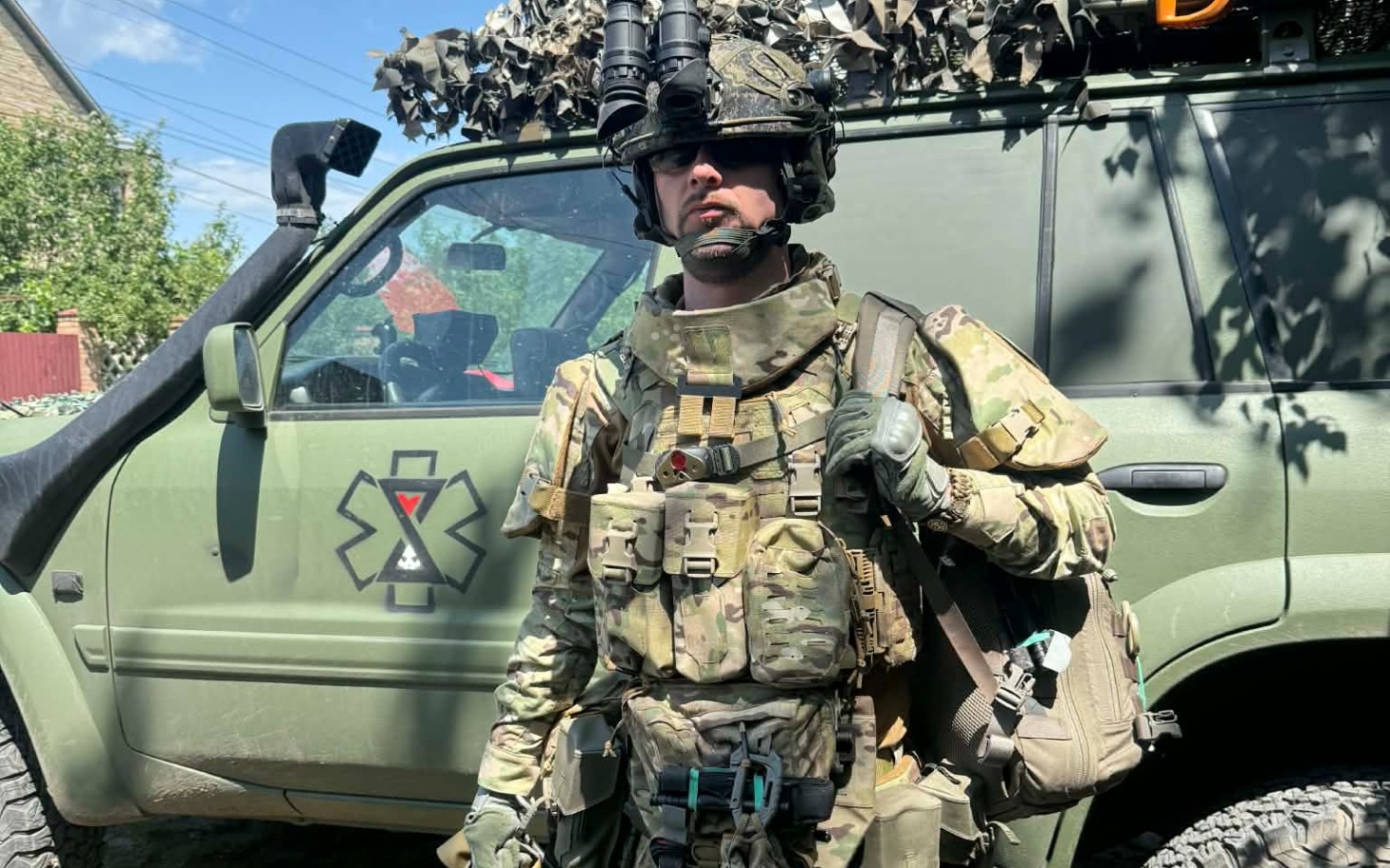 
        Żołnierz w pełnym umundurowaniu, stojący obok pojazdu.
    