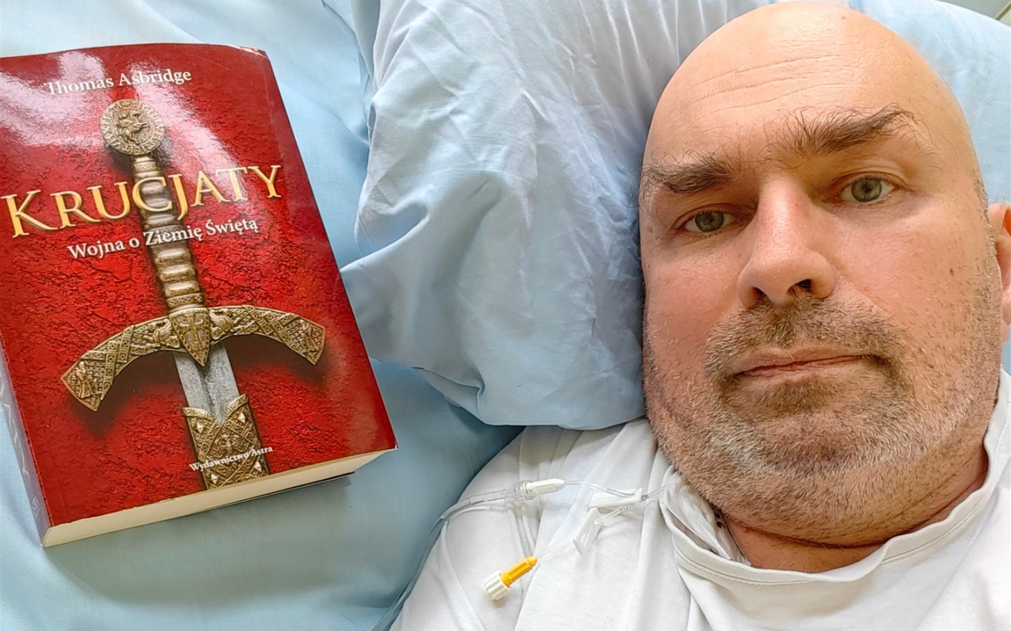 
        Mężczyzna w łóżku z książką 'Krucjaty' obok siebie.
    