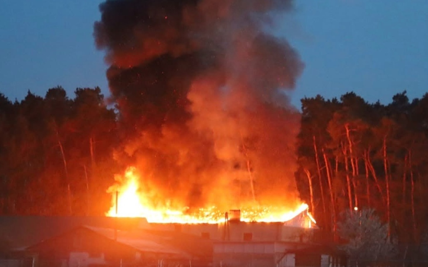
        Pożar w lesie, dym i ogień wydobywają się z budynku.
    