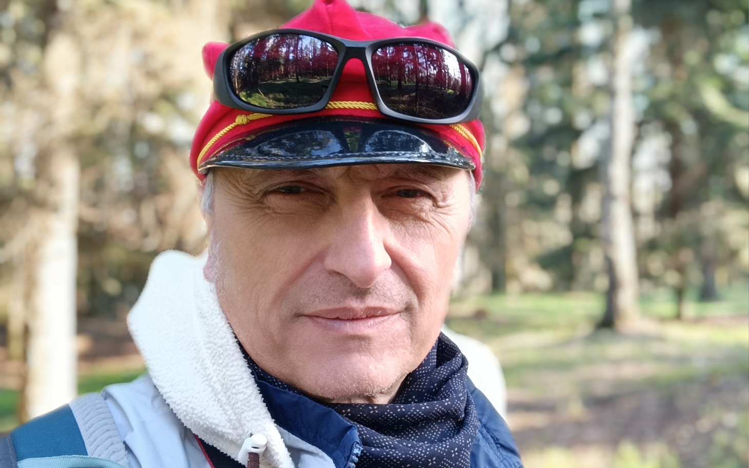 
        Mężczyzna w okularach przeciwsłonecznych na tle lasu.
    