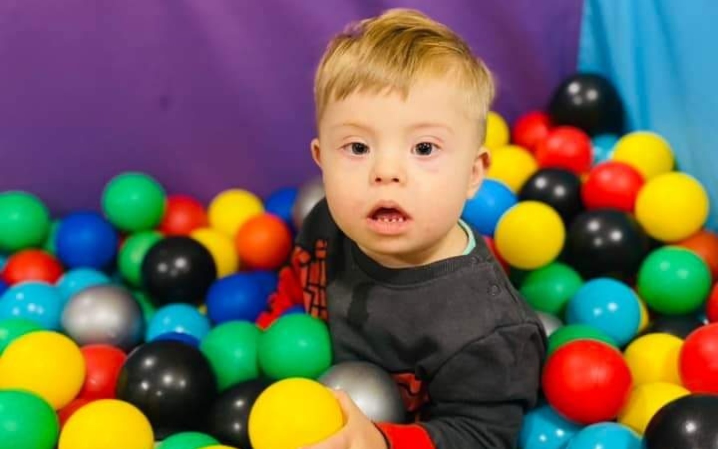 
        Chłopiec bawi się w basenie z kolorowymi piłkami.
    