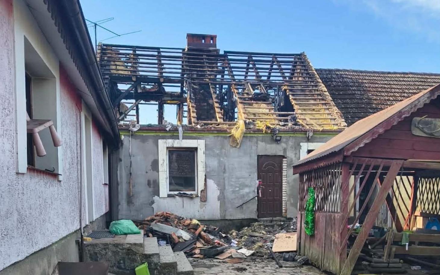 
        Zniszczony dach budynku po pożarze, widok z zewnątrz.
    