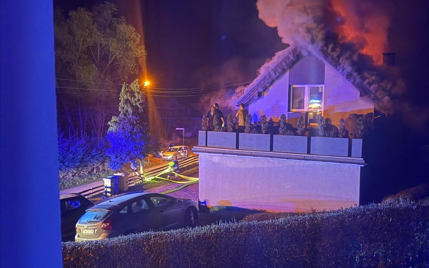 
        Pożar w budynku, strażacy pracujący w nocy.
    