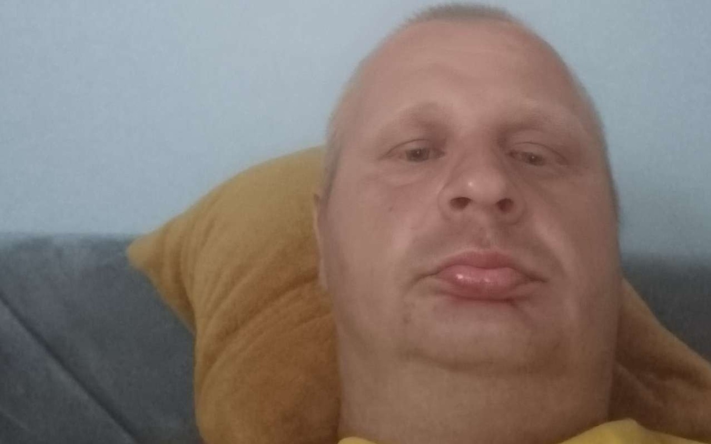 
        Mężczyzna leżący na kanapie, z wyrazem twarzy.
    