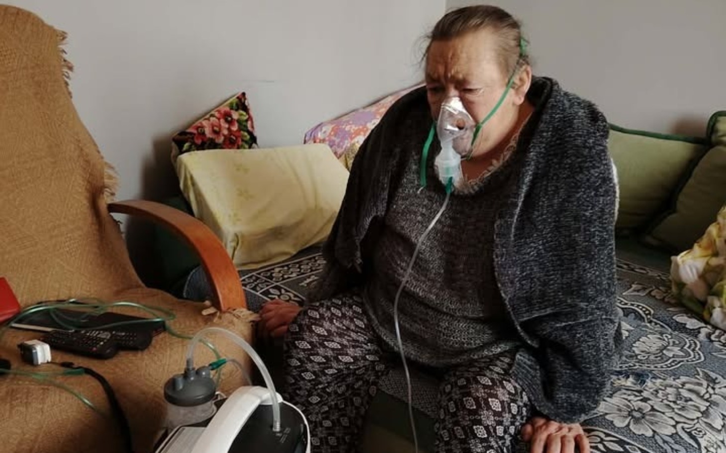 
        Starsza kobieta korzystająca z aparatu tlenowego w domu.
    