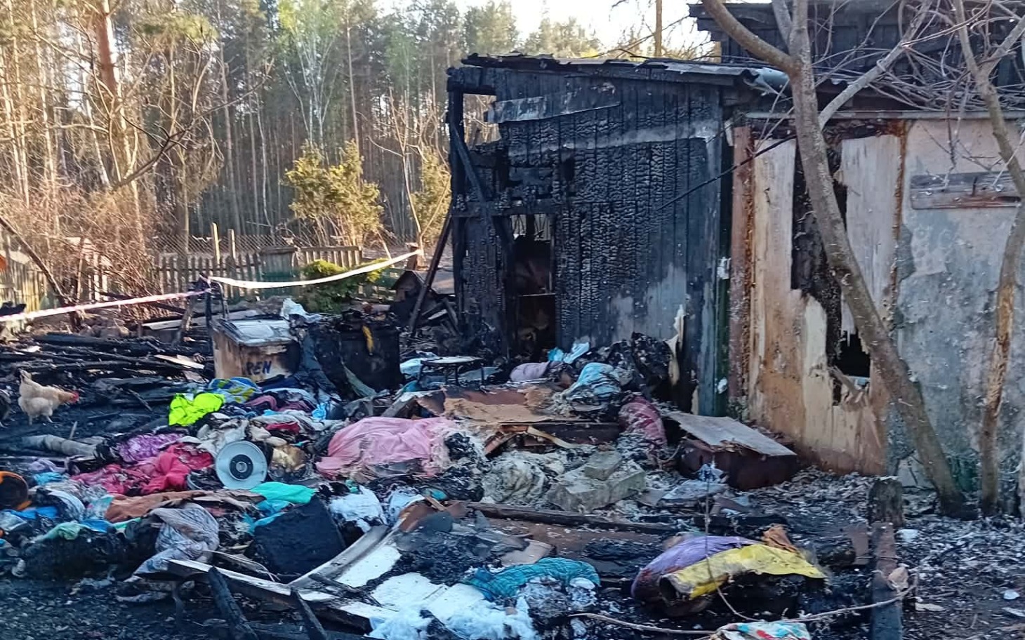 
        Zniszczony budynek po pożarze, wokół zgliszcza.
    