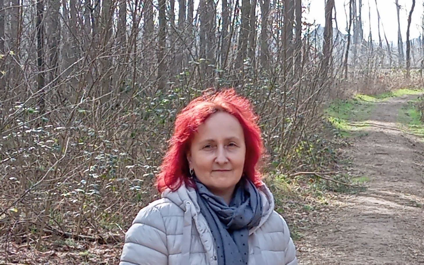 Kobieta z czerwonymi włosami spacerująca w lesie.