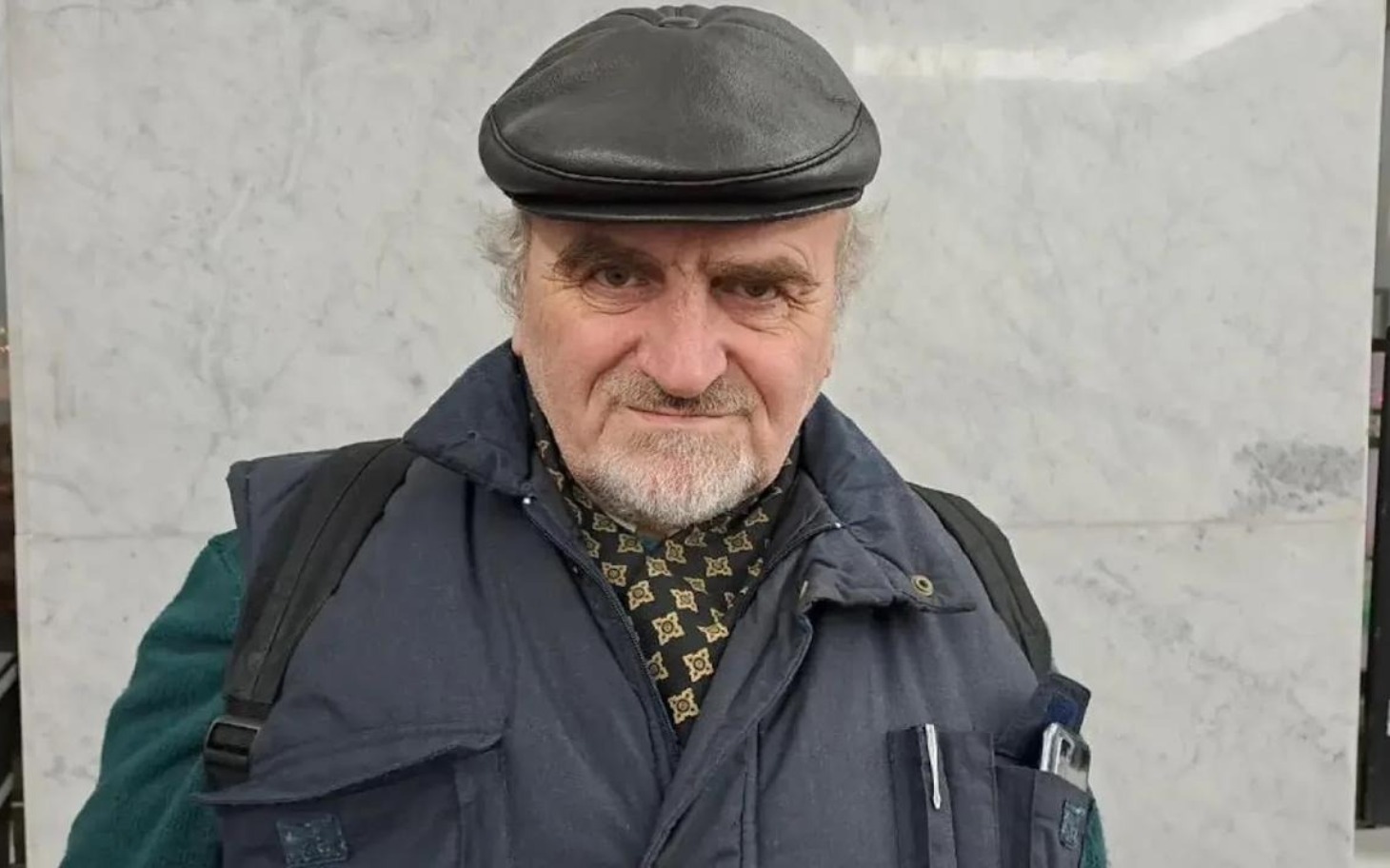 
        Mężczyzna w czapce, uśmiechający się do kamery.
    