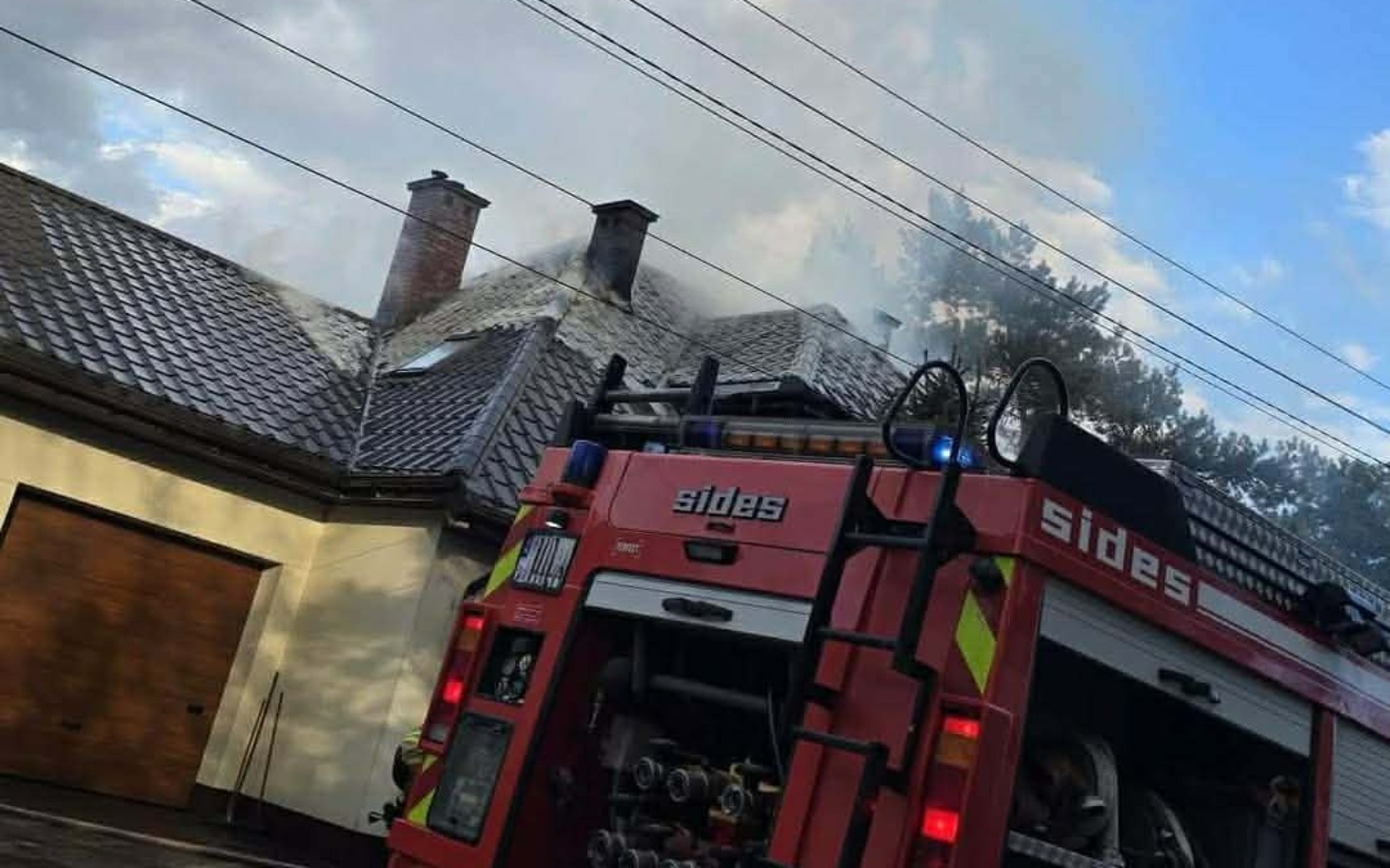 
        Straż pożarna gasząca pożar na dachu budynku.
    