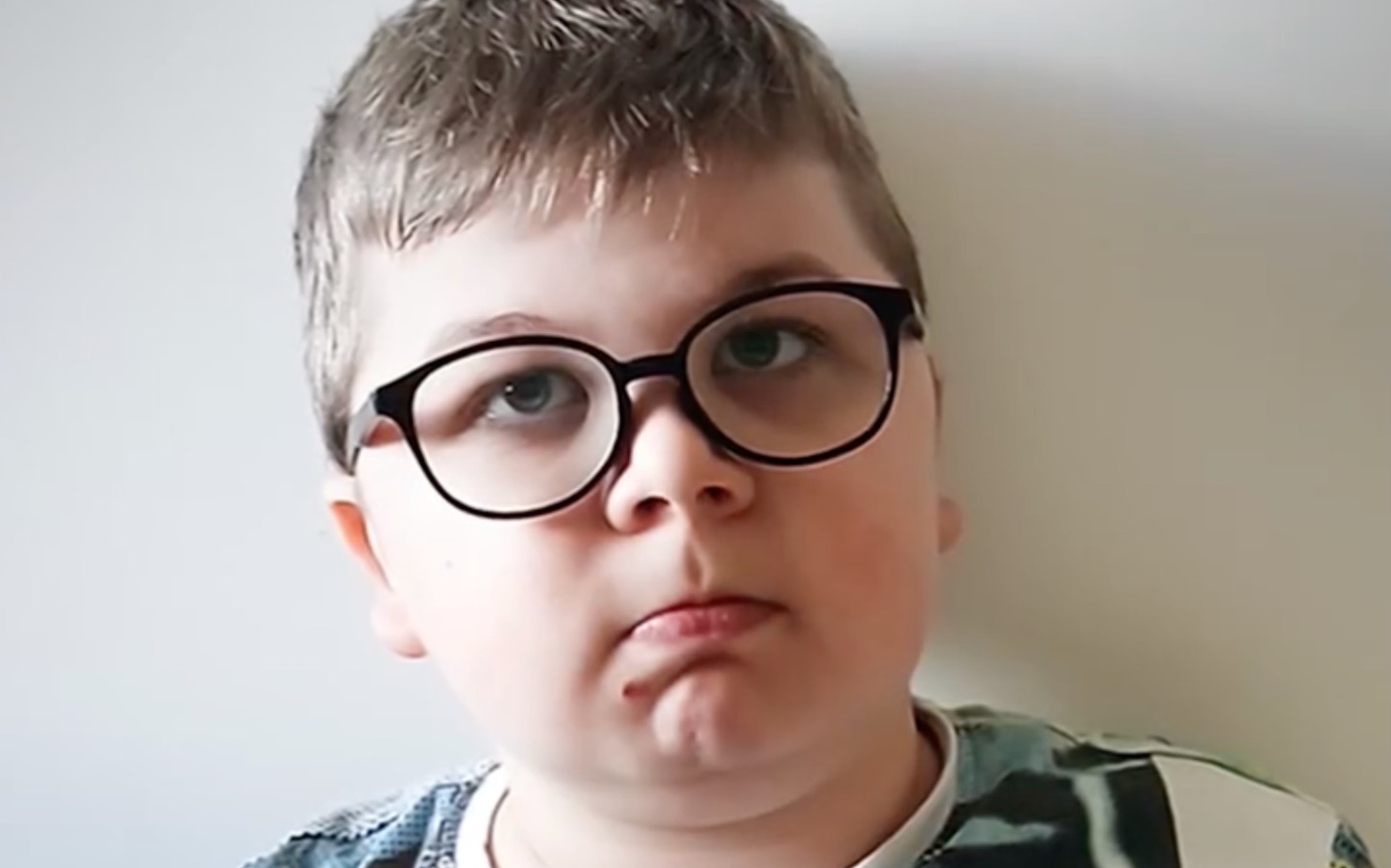 Chłopiec w okularach z poważnym wyrazem twarzy.