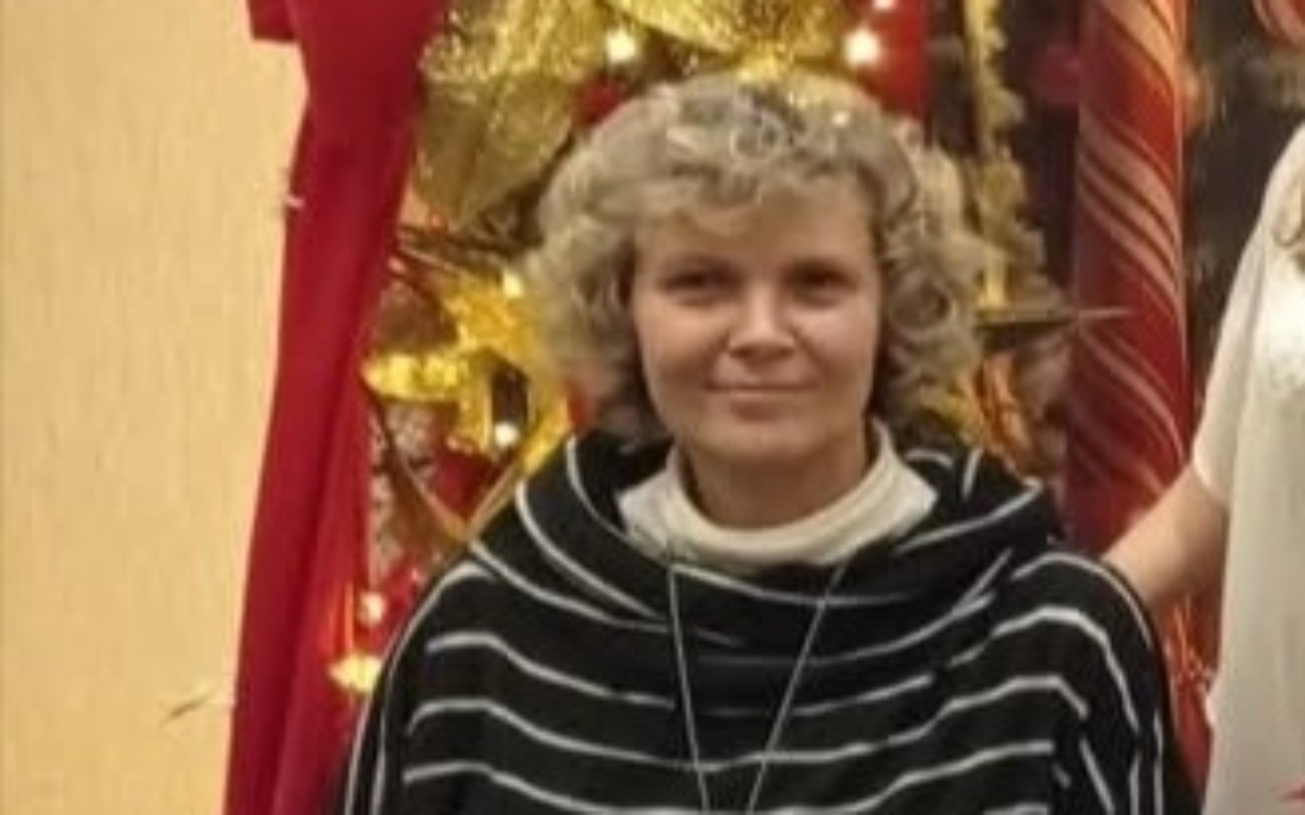 
        Kobieta w swetrze, uśmiechająca się na tle dekoracji świątecznych.
    