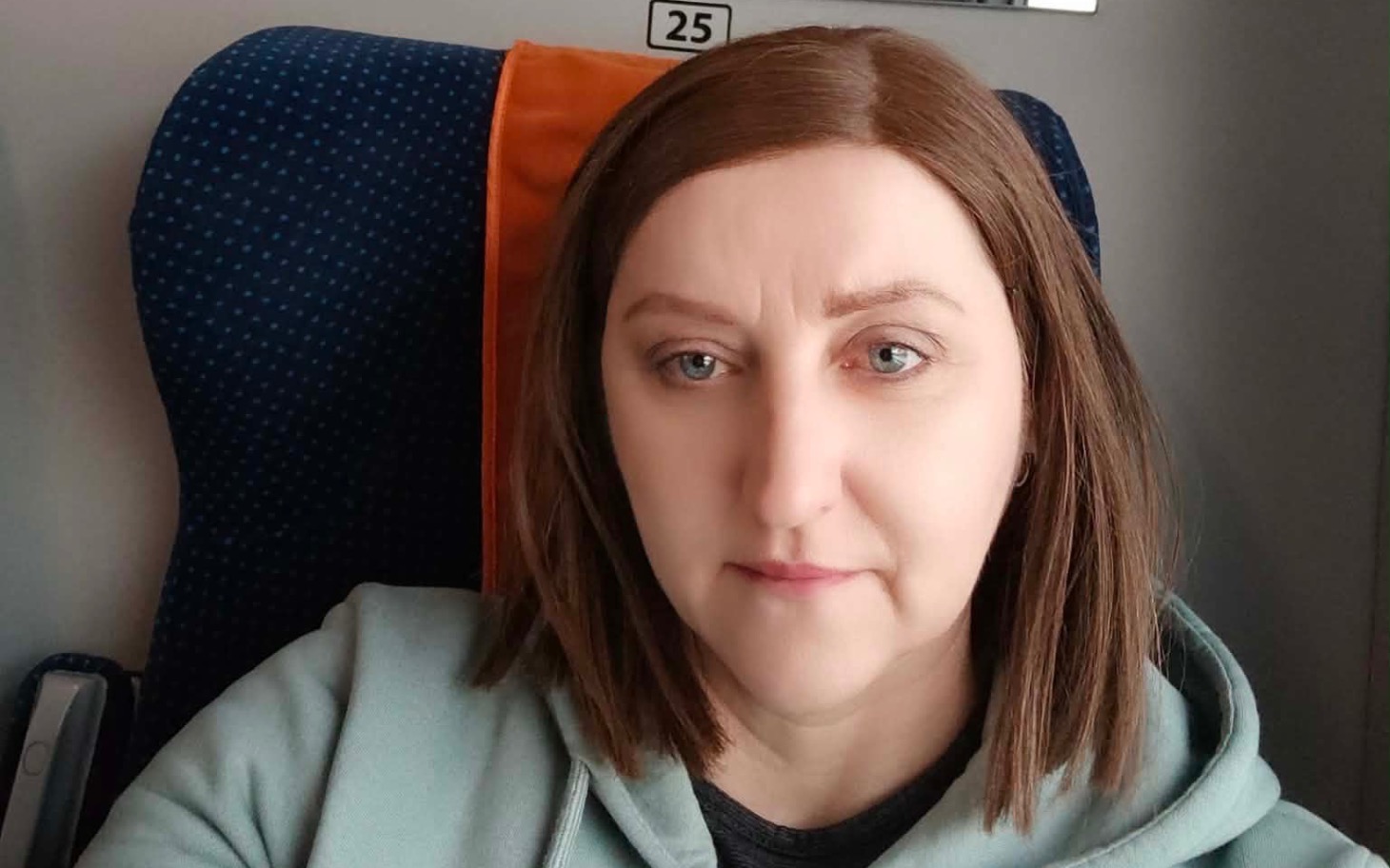 
        Kobieta w pociągu, z zamyśloną miną, w trakcie podróży.
    