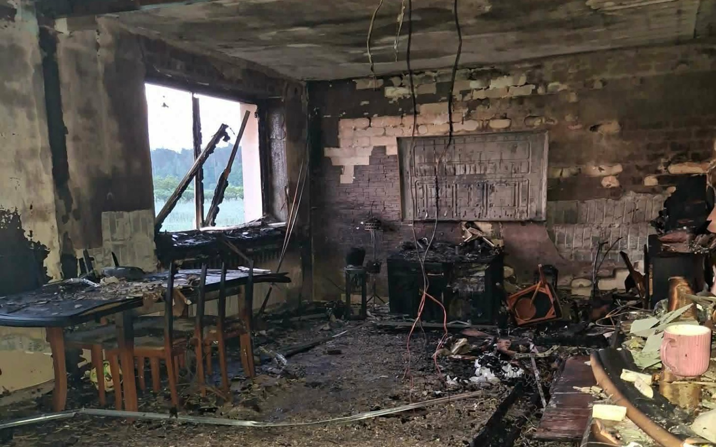 
        Zniszczone wnętrze pożaru, z popiołem i uszkodzonymi meblami.
    