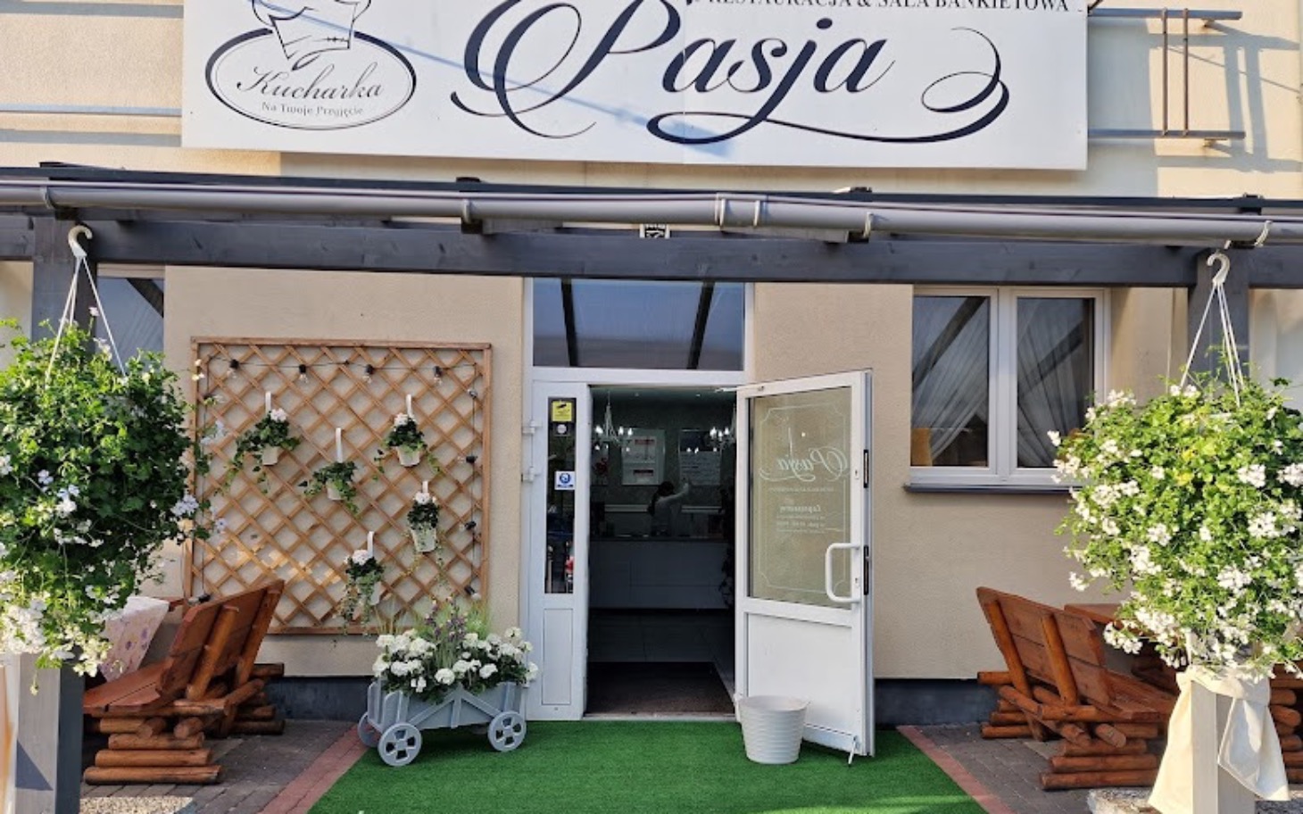 
        Wejście do restauracji z kwiatami w donicach.
    