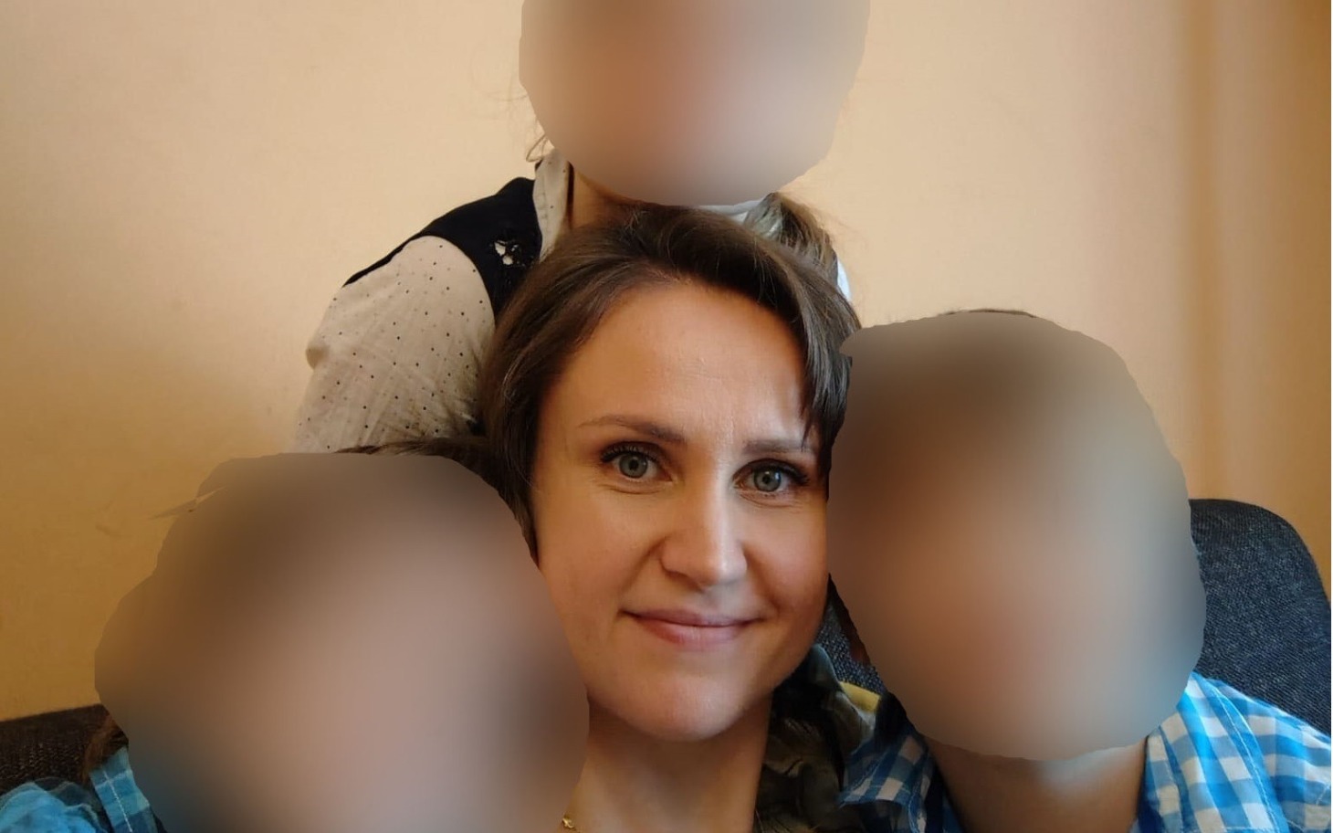 
        Kobieta z dziećmi, uśmiechnięta na kanapie.
    