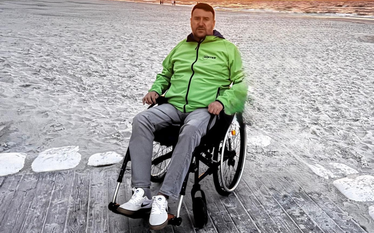 Mężczyzna na wózku inwalidzkim na plaży, cieszący się widokiem.