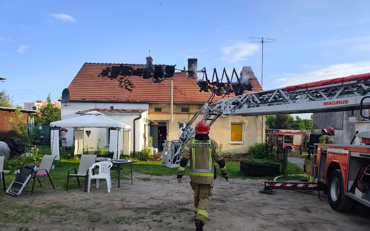 
        Strażak w akcji, gaszący pożar na dachu domu.
    