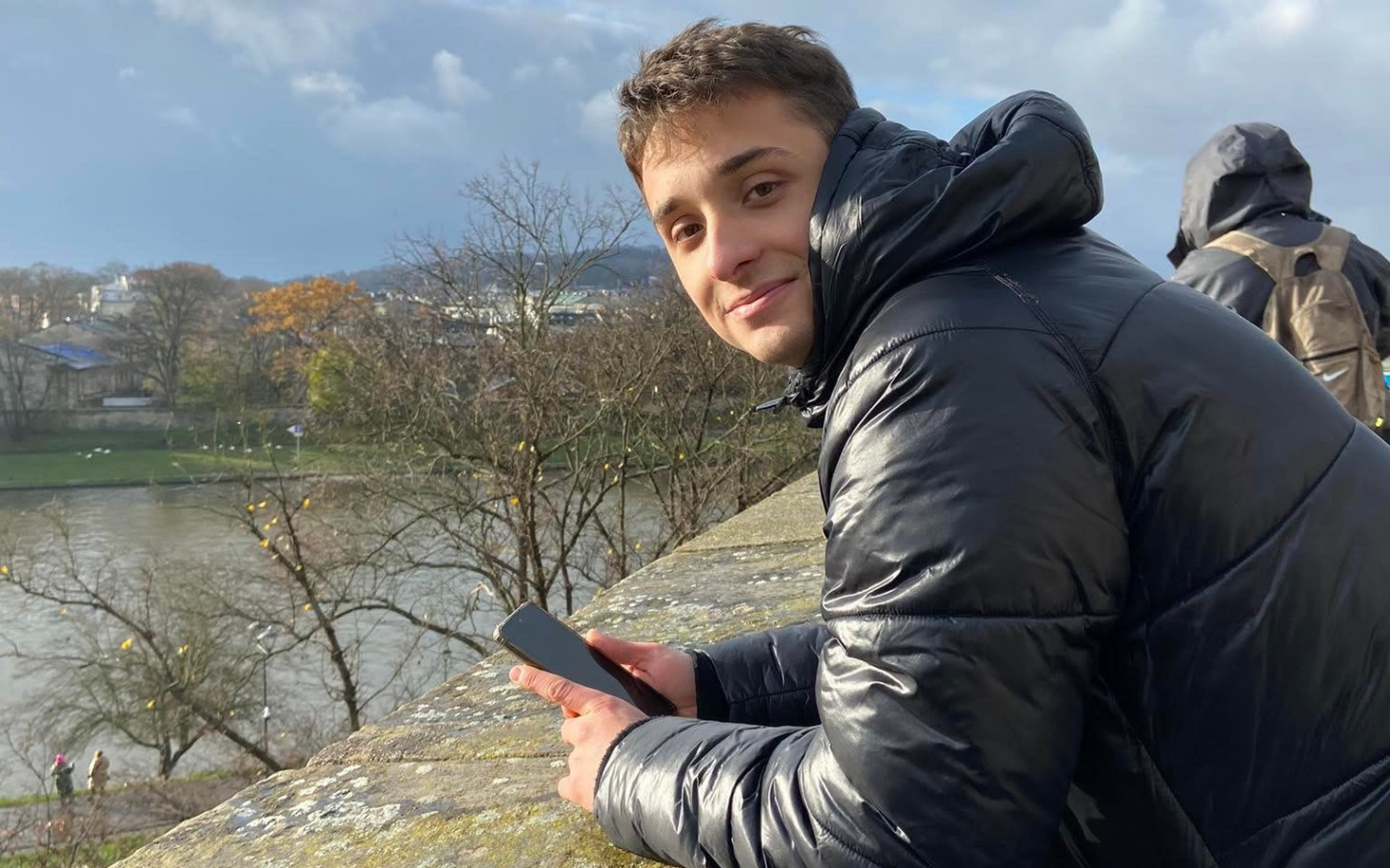 
        Mały kotek z biała plamką na piersi, w zieleni kwiatów.
    