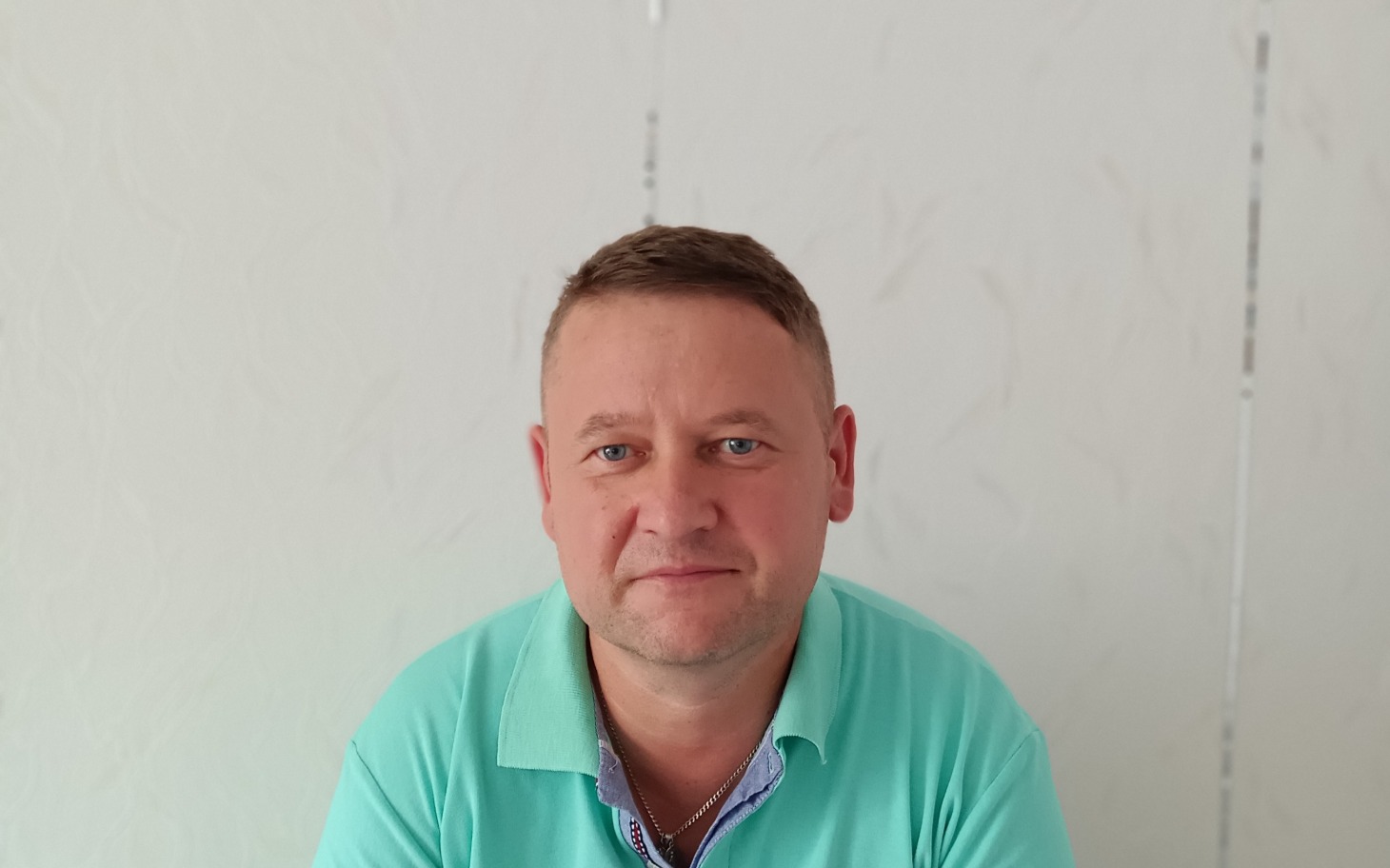 
        Blisko twarzy jubilera z butelką na tle białej ściany.
    
