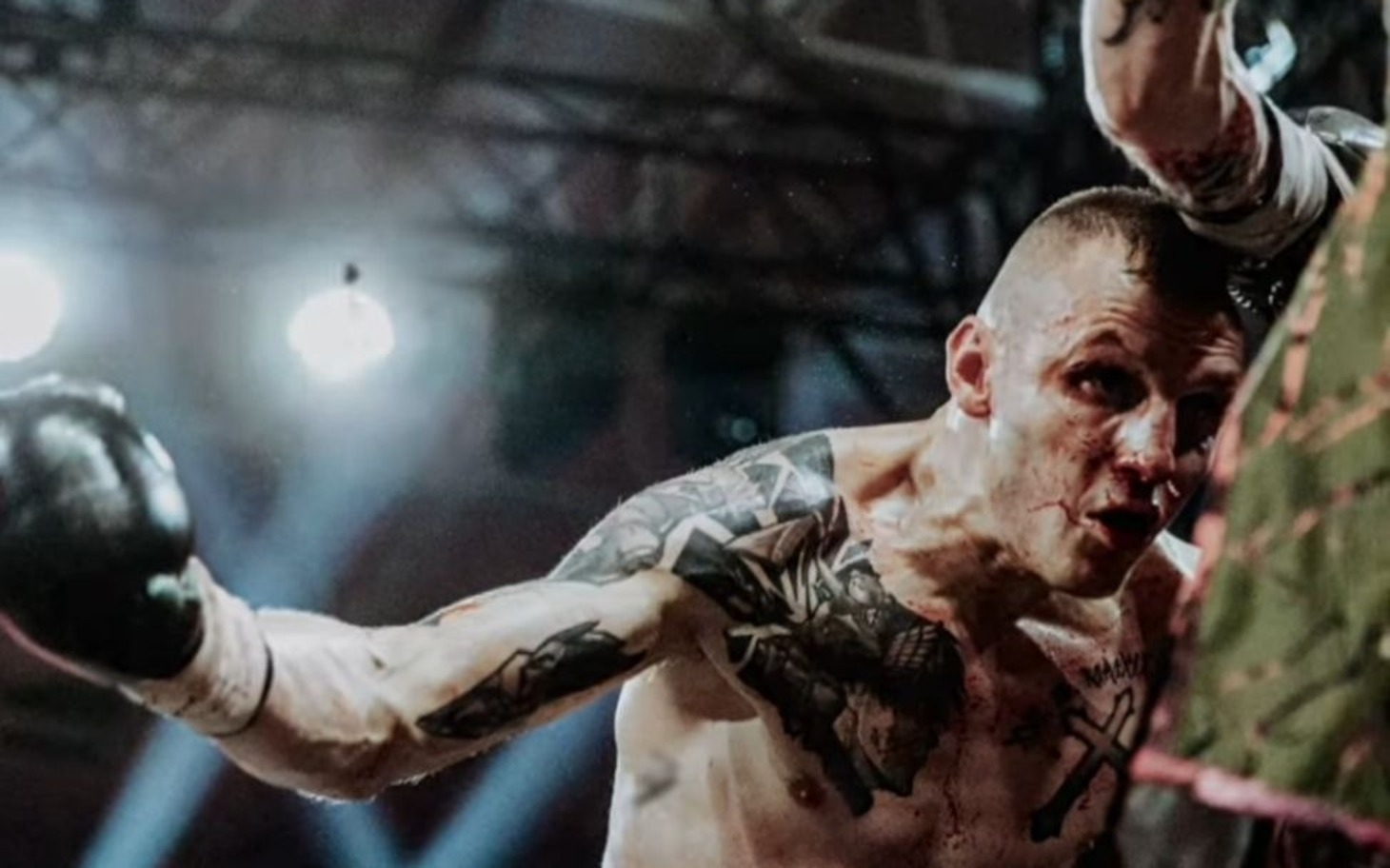 
        Mocno wytatuowany bokser z wyszarpaną twarzą, sportowe potyczki.
    