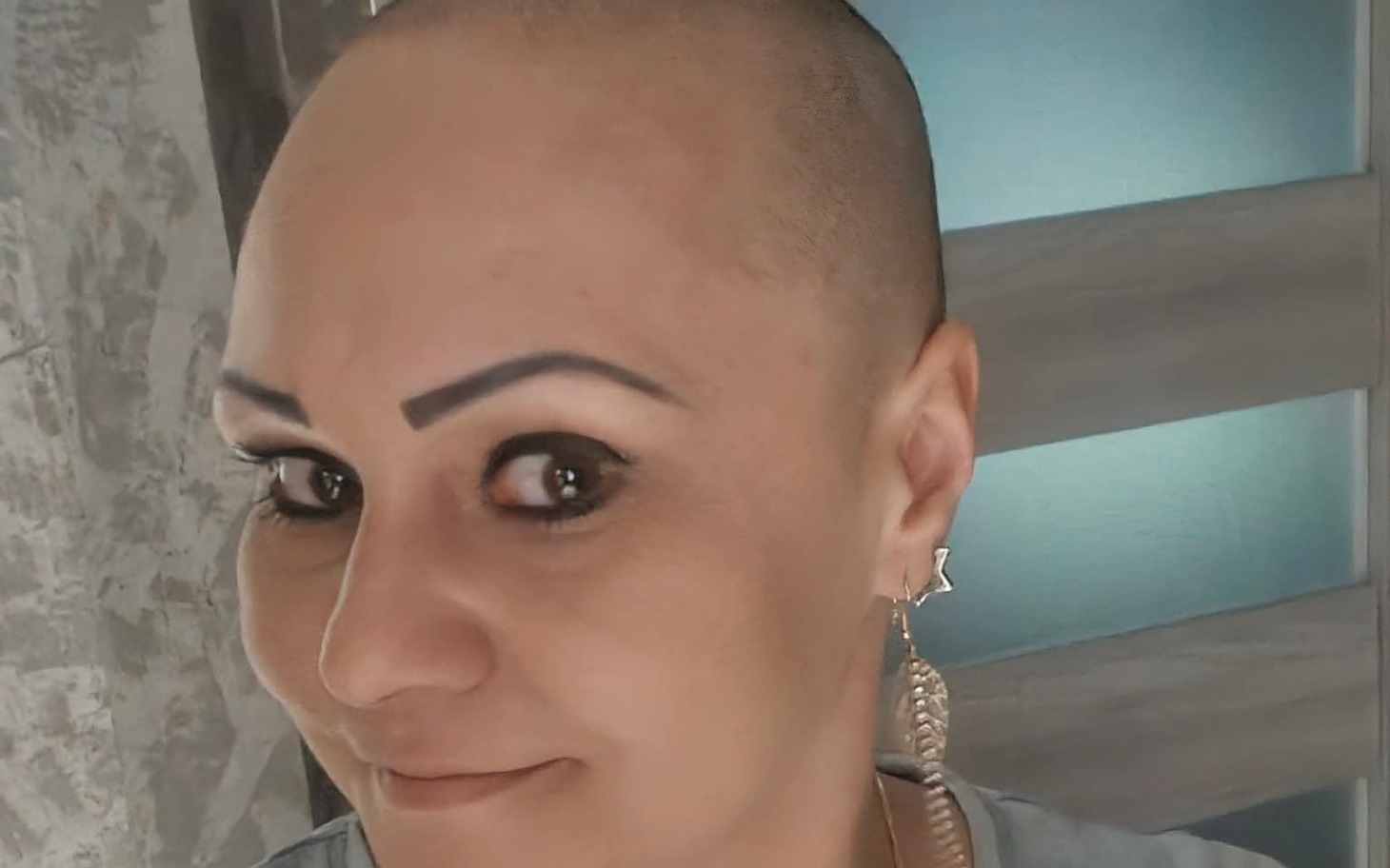 
        Kobieta z krótkimi włosami i üparzystymi brwiami, uśmiech na twarzy.
    
