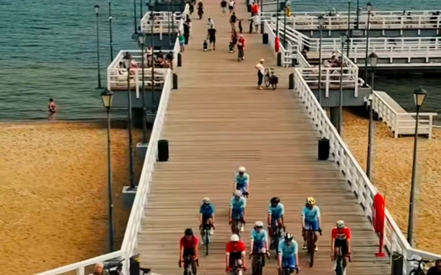 
        Grupa cyklistów na ścieżce nadmorskiej, wspólna jazda z plecakiem.
    