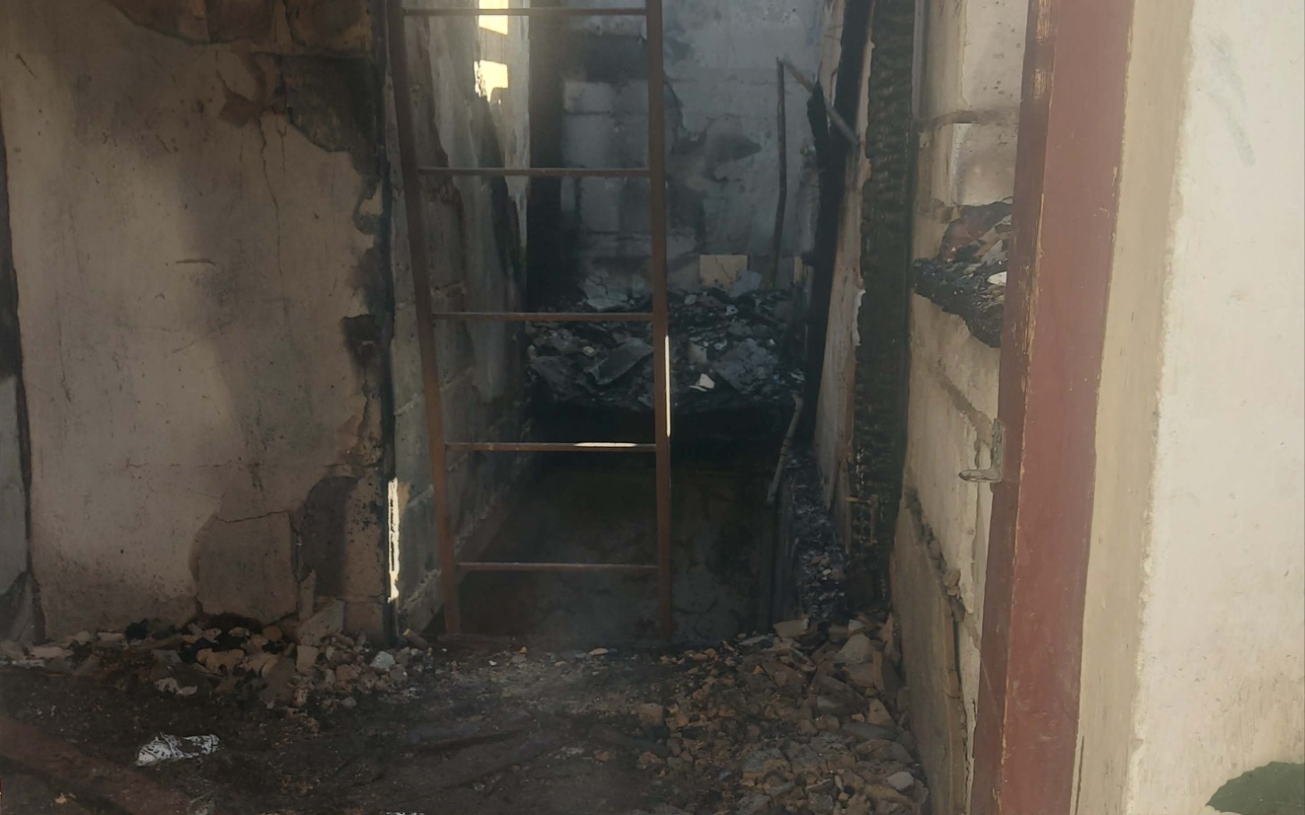 
        Zniszczone wejście z rozkruszoną podłogą i widoczną drabiną.
    